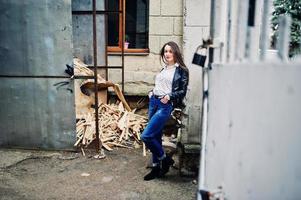 portrait d'une jeune fille élégante portant une veste en cuir et un jean déchiré dans les rues de la ville. style de modèle de mode de rue. photo