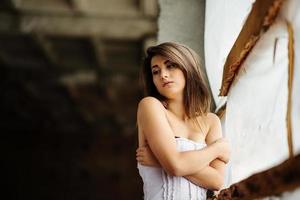 portrait en gros plan d'une jeune fille brune mignonne posée sur un lieu abandonné. photo