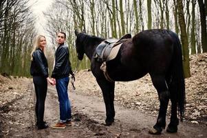 jeune couple élégant amoureux près de cheval à la forêt d'automne. photo