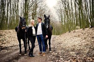 jeune couple élégant amoureux près des chevaux dans la forêt d'automne. photo