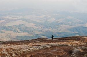 l'homme se tient sur la colline et regarde les montagnes. photo