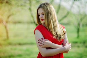 portrait de fille aux cheveux clairs sur fond de robe rouge jardin de printemps. photo