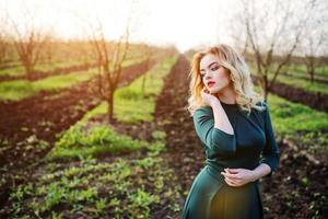 yong élégance fille blonde en robe verte sur le jardin au printemps. photo