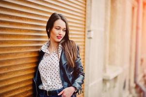 portrait d'une jeune fille élégante portant une veste en cuir et une texture d'obturateur de fond de jeans déchirés. style de modèle de mode de rue. photo