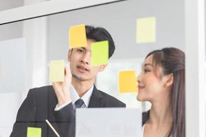 les jeunes gens d'affaires se réunissent au bureau et utilisent des post-it pour partager des idées. employé de bureau discutant ensemble dans la salle de conférence photo