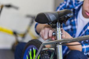 mise au point sélective d'un garçon fixant à la main un vélo, un passe-temps mécanique et des concepts de réparation photo