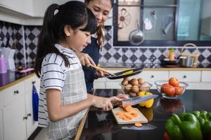 les familles asiatiques cuisinent et les parents apprennent à leurs filles à cuisiner dans la cuisine à la maison. activités familiales en vacances et heureux dans le concept de loisirs photo