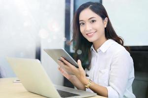 femmes d'affaires asiatiques utilisant une tablette pour travailler au bureau se détendre et sourire photo