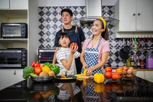 une famille heureuse a papa, maman et leur petite fille qui cuisinent ensemble dans la cuisine photo