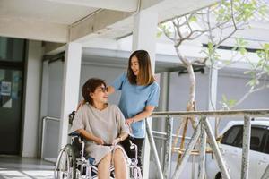physiothérapeute souriant prenant soin de l'heureux patient âgé en fauteuil roulant photo