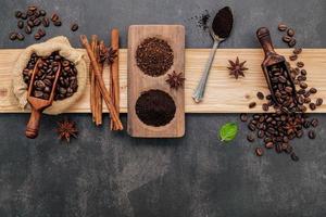 grains de café torréfiés avec de la poudre de café et des ingrédients savoureux pour préparer un café savoureux sur fond de pierre sombre. photo