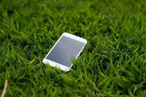 téléphone portable placé dans une herbe vert clair. chaque téléphone doit avoir une maison. notion de téléphone photo
