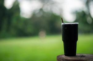 un verre d'eau noire est placé sur un poteau en bois avec un bouchon, le concept d'eau potable et un verre d'eau. photo