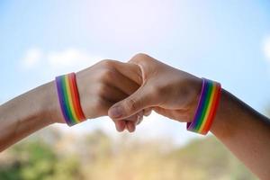 bracelets en caoutchouc arc-en-ciel aux poignets d'un couple de garçons asiatiques avec arrière-plan flou, concept pour la célébration de la communauté lgbt pendant le mois de la fierté ou en juin dans le monde entier. photo