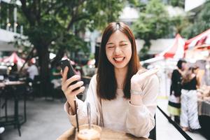 femme asiatique d'affaires adulte avec utilisation de téléphone portable pour les appels internet au café intérieur le jour. photo