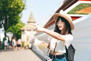 jeune asiatique heureux lunettes fille voyageur pointant vers le point de repère. photo