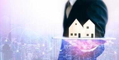 agent immobilier d'affaires homme tenant une tablette numérique avec modèle de maison pour le concept de médias en ligne photo