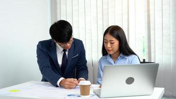 un directeur masculin asiatique enseigne au personnel la comptabilité à leur bureau. photo