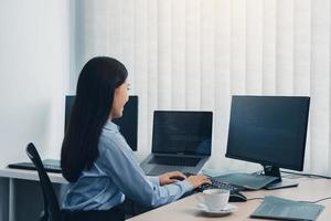 femme d'affaires travaillant sur un écran d'ordinateur de bureau professionnel et assise à son bureau et travaillant sur un nouveau logiciel. photo