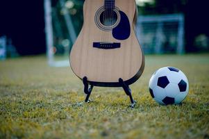 la guitare et le football sont placés dans des pelouses vertes. des idées de musique et de sport et il y a un espace de copie. photo