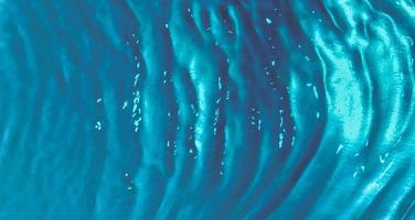 vue de dessus des vagues d'eau avec des bulles sur un fond turquoise. texture de la surface de l'eau photo