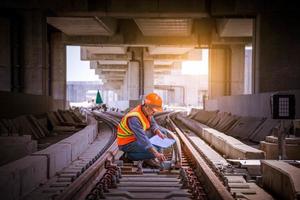 ingénieur chemin de fer en cours de vérification du processus de construction essai de train et vérification des travaux ferroviaires sur la gare avec communication radio .ingénieur portant un uniforme de sécurité et un casque de sécurité au travail. photo