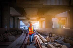 ingénieur chemin de fer en cours de vérification du processus de construction essai de train et vérification des travaux ferroviaires sur la gare avec communication radio .ingénieur portant un uniforme de sécurité et un casque de sécurité au travail. photo