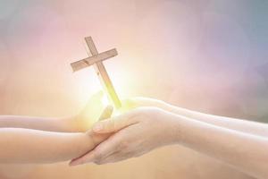 main de bébé et main de maman tenant une croix électroluminescente demandant la bénédiction de dieu photo