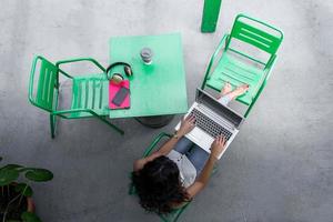 pigiste détendu et méconnaissable naviguant sur un ordinateur portable sur la terrasse photo