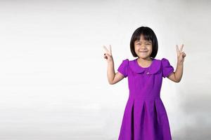 portrait de jolie fille asiatique d'une petite fille joyeuse en t-shirt gris regardant la caméra et fond isolé clignotant. fille caucasienne émotionnelle. enfant heureux photo