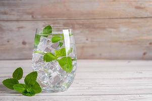 feuille de menthe dans une boisson fraîche froide en verre sur fond de bois. photo