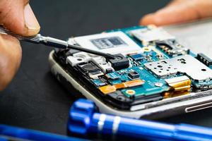 technicien réparant l'intérieur du téléphone portable en fer à souder. circuit intégré. le concept de données, de matériel, de technologie. photo