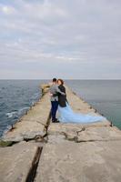 séance photo de mariage d'un couple au bord de la mer. robe de mariée bleue sur la mariée.