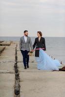 séance photo de mariage d'un couple au bord de la mer. robe de mariée bleue sur la mariée.