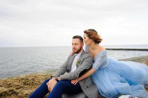 séance photo de mariage d'un couple au bord de la mer. robe de mariée bleue sur la mariée.