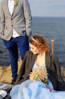 séance photo de mariage d'un couple au bord de la mer. robe de mariée bleue sur la mariée.