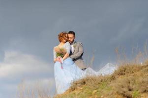 séance photo de mariage d'un couple au bord de la mer. robe de mariée bleue sur la mariée.