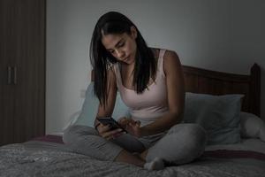 femme parcourant son smartphone sur son lit photo