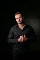 portrait en studio d'un jeune homme de race blanche dans un blazer noir, regardant la caméra, debout sur fond de studio uni photo