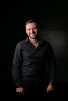 portrait en studio d'un jeune homme de race blanche dans un blazer noir, regardant la caméra, debout sur fond de studio uni photo