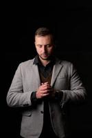 portrait en studio d'un jeune homme de race blanche dans un blazer noir, regardant la caméra, debout sur fond de studio uni photo