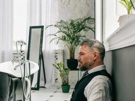 bel homme d'affaires écossais élégant et courageux mature en kilt et costume dans la salle de bain. style, travail à domicile, mode, mode de vie, culture, concept ethnique. photo