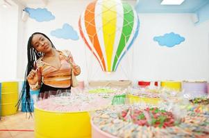 dame afro-américaine du millénaire au magasin de bonbons avec des lolipops. photo