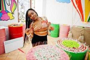 dame afro-américaine du millénaire au magasin de bonbons avec des lolipops. photo