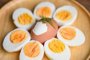 oeufs petit-déjeuner, oeufs frais menu nourriture oeufs bouillis dans une assiette en bois décorée de feuilles fond d'aneth vert, coupé en deux jaunes d'oeufs pour cuisiner une alimentation saine photo