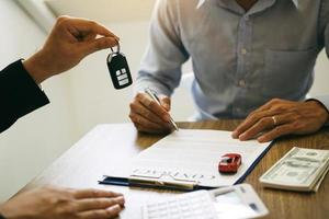 les acheteurs de voitures neuves signent les documents contractuels pour les achats de voitures neuves dans la salle d'exposition, le bureau du vendeur. photo