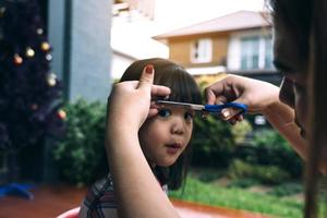 maman coupait les cheveux de sa fille à la maison. photo