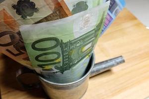 billets en euros dans un cylindre d'arrosage galvanisé. photo