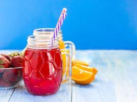 smoothie frais d'ananas et de fraise dans des verres avec des fruits sur un fond rustique en bois bleu photo