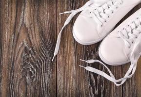 baskets blanches sur une surface en bois sombre. chaussures pour femmes dans le style de la mode sportive photo